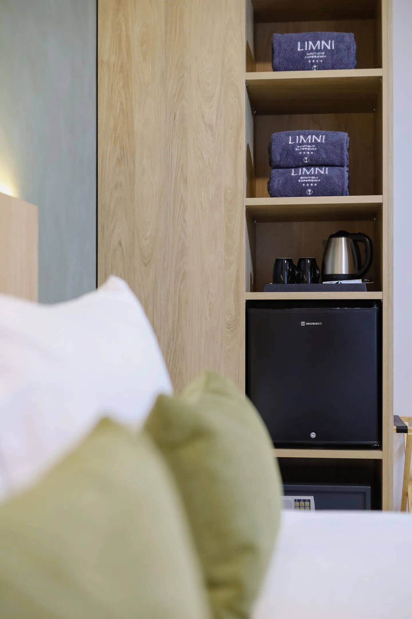A hotel room with a bed, a minibar, and a wooden wardrobe.