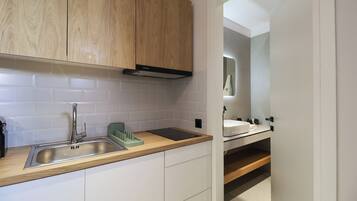 Una cocina moderna con un lavamanos de acero inoxidable, armarios de madera y un salpicadero de azulejos blancos.
