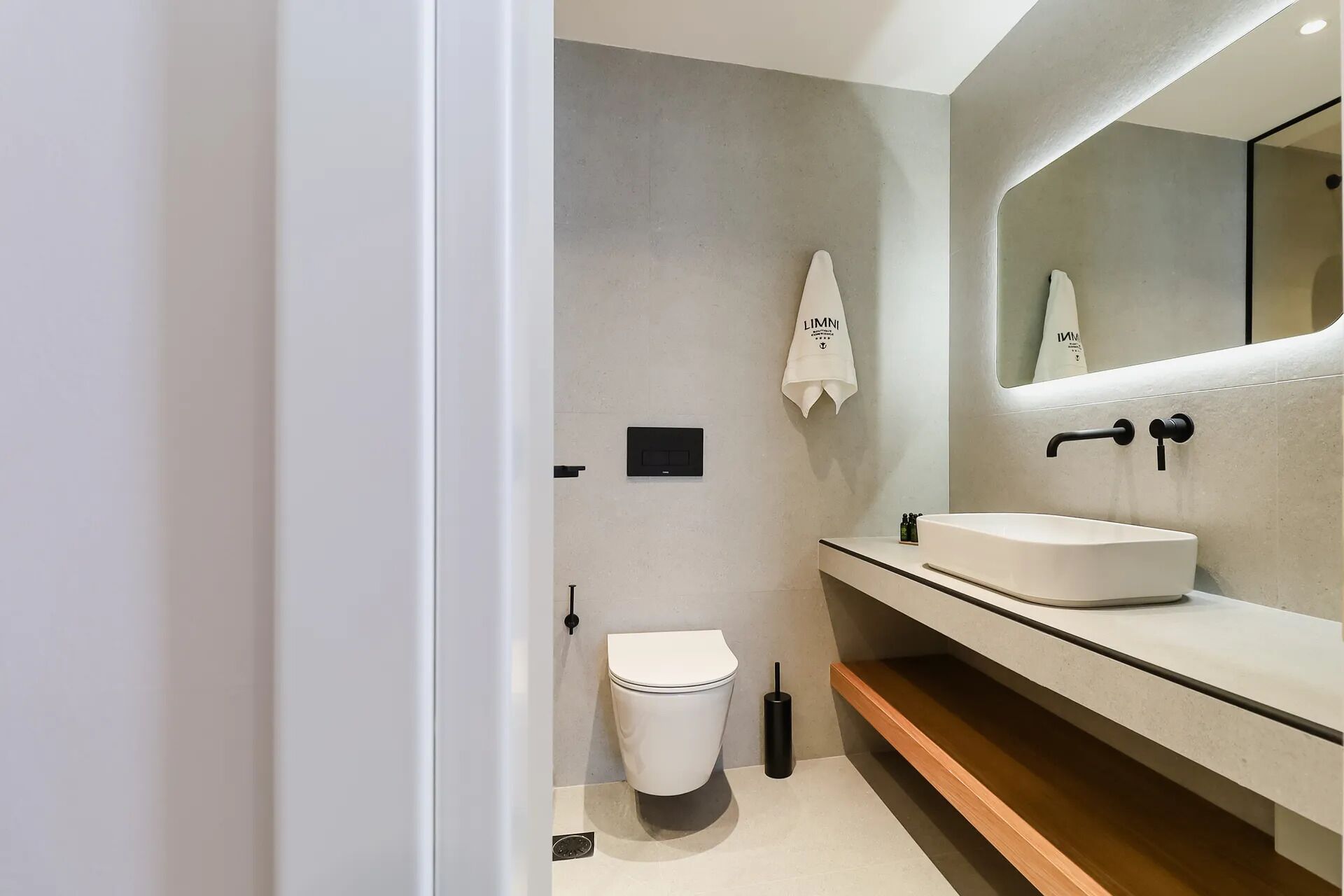 A modern bathroom with a toilet, sink, and a towel hanging on the wall.