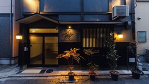 A building with a dark facade, a gated entrance, and potted plants in front. - Kyoto Amazing - The Wizard of Oz (Kyoto)