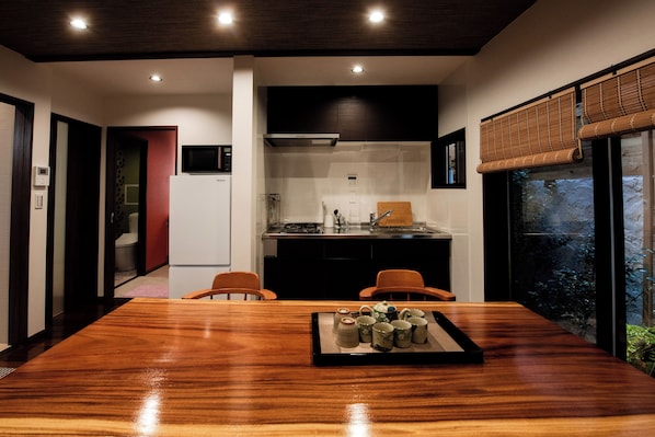 Una cocina moderna con una isla central, un comedor con mesa de madera y vistas a zonas verdes a través de amplios ventanales.