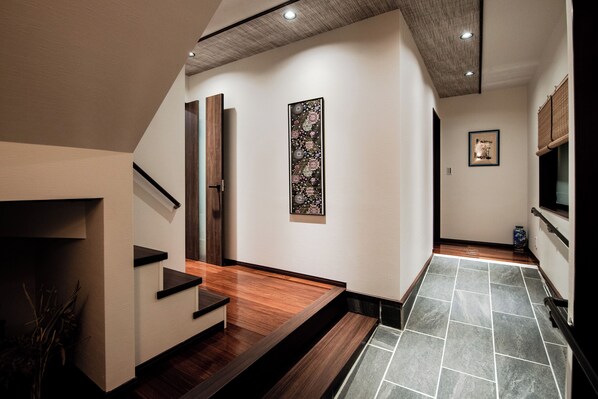 A modern interior with a wooden staircase, a decorative wall piece, and a tiled floor.