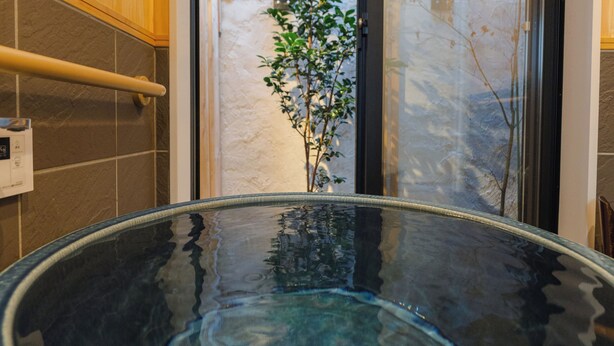 A hot tub with a glass top, wooden walls, a bamboo blind, and a plant in the background. - Kyoto Amazing - The Wizard of Oz (Kyoto)