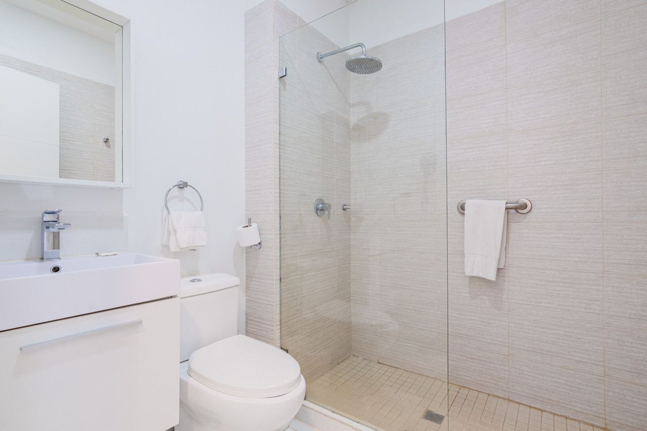 Un bagno moderno con doccia vetrata, lavandino bianco e water.