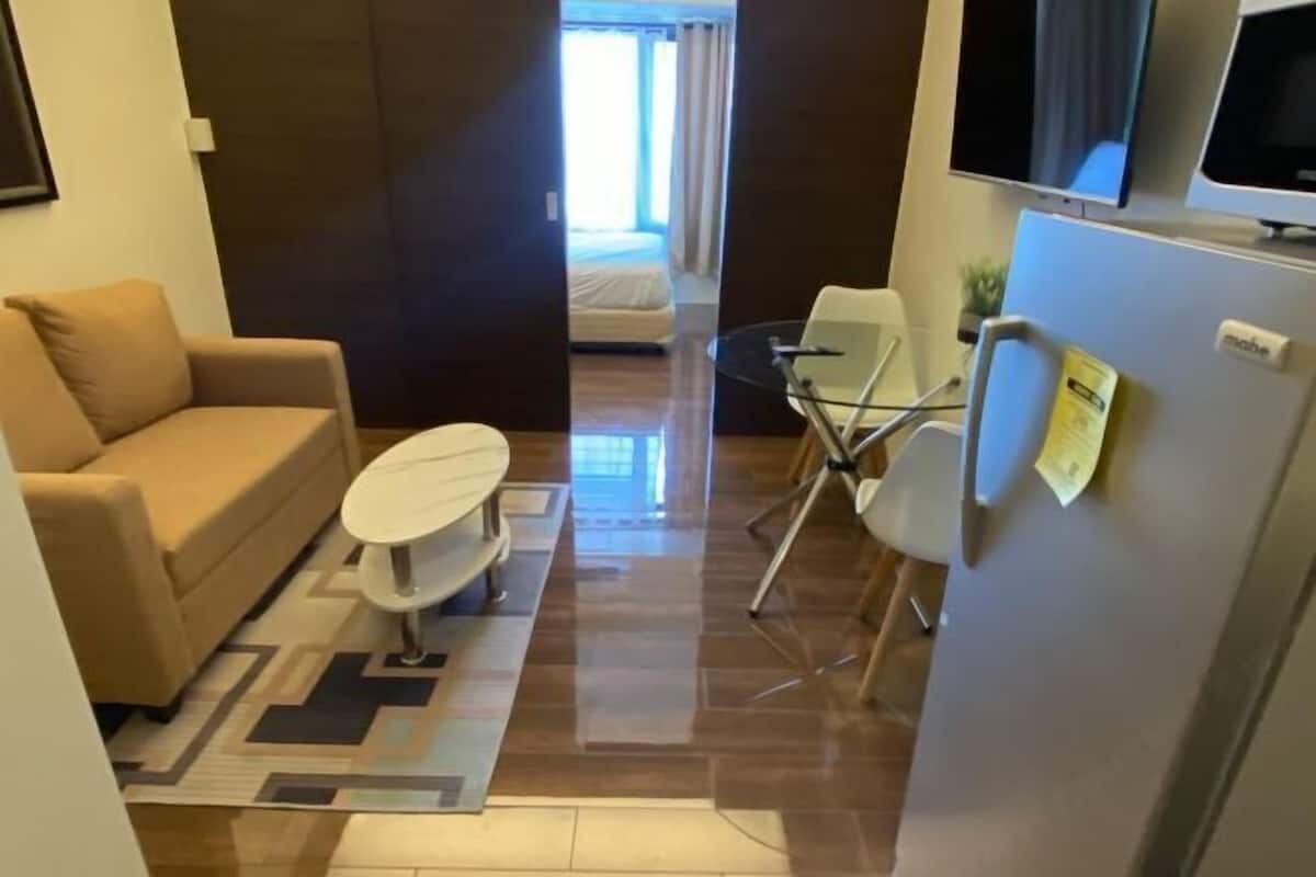 Zona d'estar senyorial amb sofà, taula rodona petita, televisió i nevera.