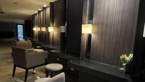 Un hall d’hôtel moderne avec un long comptoir d’accueil, plusieurs fauteuils et un grand miroir.