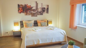 Ein Schlafzimmer mit einem Bett, Nachttischlampen, einer Topfpflanze und Bildern an der Wand.