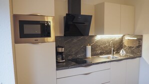 Eine moderne Küche mit integriertem Mikrowellenherd, einer Kaffeemaschine und einem Marmor-Arbeitsplatten-Spülbecken.