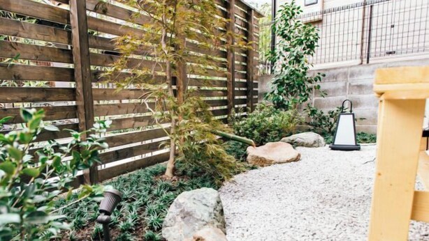 Un jardín con cerca de madera, rocas y un camino de grava.