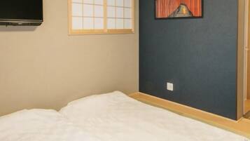 A room with a bed, a TV mounted on the wall, a window with a view, and a painting on the wall.