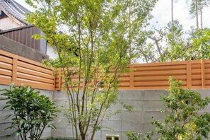 Un edificio de estilo japonés tradicional con una cerca de madera y un muro de piedra.