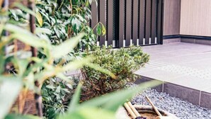 Un jardín interior moderno con un pequeño arbusto, un banco de madera y un sendero de piedra.