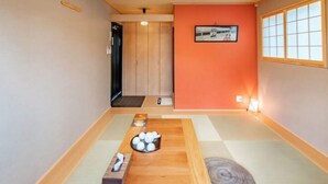 Una habitación con tatamis, una mesa de madera, un cuadro en la pared y un puertas correderas al fondo.