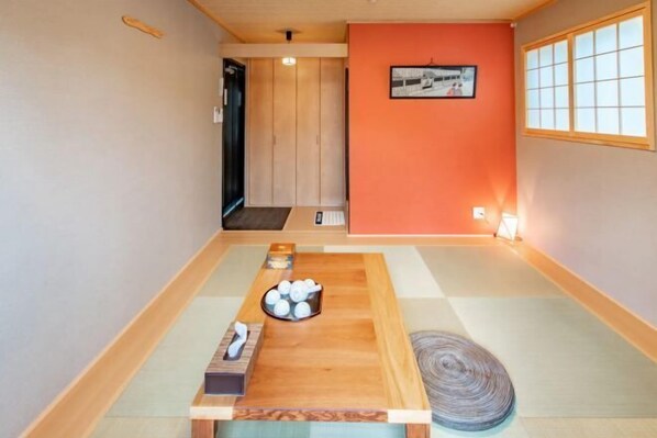 Una habitación con tatamis, una mesa de madera, un cuadro en la pared y un puertas correderas al fondo.