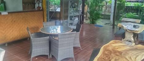 An outdoor patio with wicker furniture, a round table, and a wooden sculpture.
