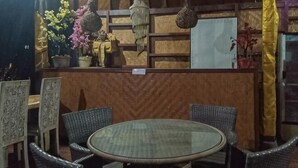 A round table with wicker chairs, a wooden partition, and potted plants.