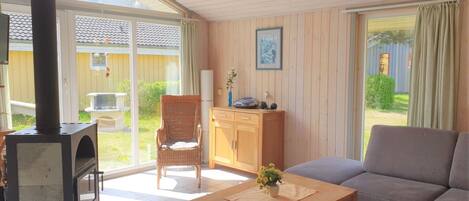 Un salon chaleureux avec un canapé, une table en bois, un fauteuil en osier et une cheminée.