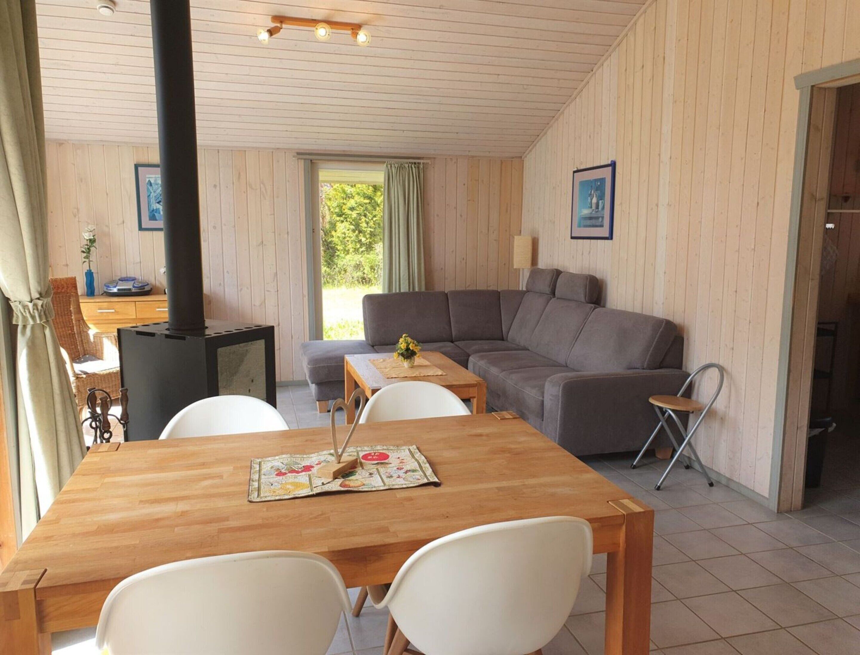 Una habitación acogedora con detalles de madera, un sofá, una mesa de comedor con sillas y una estufa de leña.