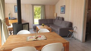 Une pièce chaleureuse avec un décor intérieur en bois, un canapé, une table à manger avec des chaises et un poêle à bois.