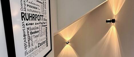 Un escalier orné d’un panneau encadré sur lequel figure une liste de mots allemands, ainsi que deux lampes fixées au mur.