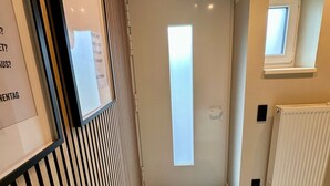 A modern hallway with a wooden panel wall, a framed sign, a door with a frosted glass panel, a small window, and a radiator. - Vacation apartment with lake view in Hattingen - an oasis of well-being in the middle of the Pott! (Hattingen)