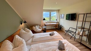 A hotel room with two beds, a desk, a chair, a TV, and a view of the sea. - Vacation apartment with lake view in Hattingen - an oasis of well-being in the middle of the Pott! (Hattingen)