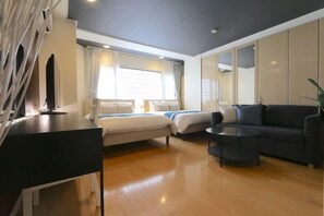 A hotel room with a bed, a sofa, a coffee table, and a TV. - ELLE Namba Villa (Osaka)