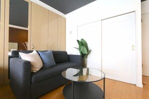 Een moderne woonkamer met een bank, een glazen bijzettafeltje en een potplant.