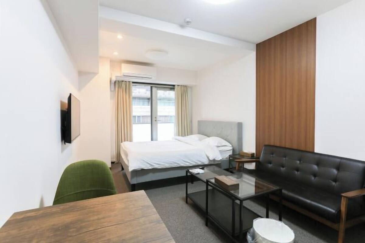 A hotel room with a bed, a sofa, a coffee table, and a TV.