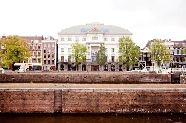 A historic building with a central dome, flanked by traditional European architecture, situated by a canal. - Hotel Prinsenhof Amsterdam (Amsterdam)
