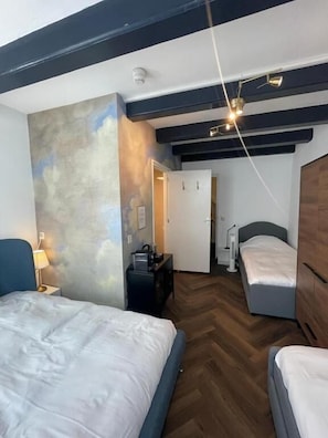 A room with two beds, a desk, a lamp, and a wardrobe. - Hotel Prinsenhof Amsterdam (Amsterdam)