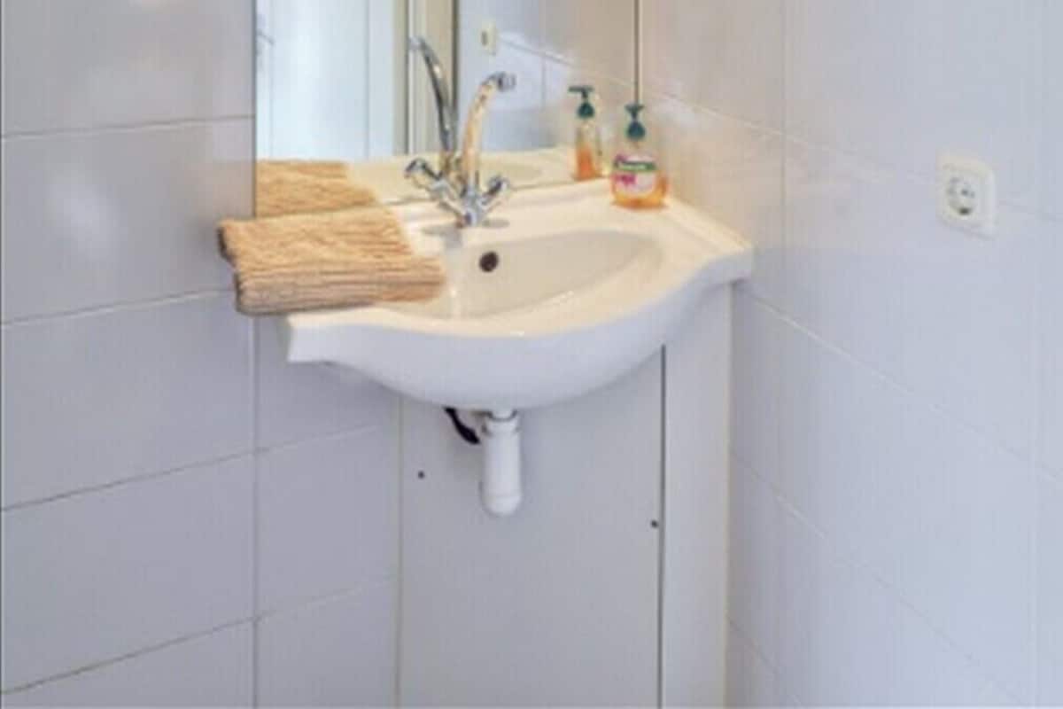 A bathroom with a white sink, a mirror, and a towel rack.