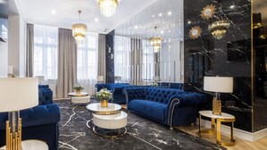 Una sala de estar moderna con un sofá azul, mesas de centro redondas y una lámpara de araña.