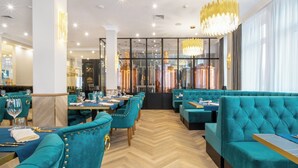 Un restaurante con asientos tapizados en color turquesa, suelo de madera con diseño de espiga y modernas lámparas de araña.