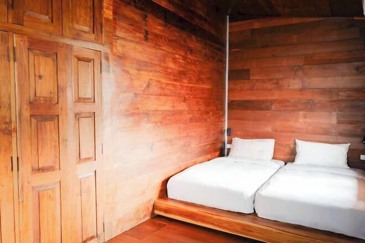 Une pièce de style cabane en bois, avec un lit, des murs en bois et une porte.