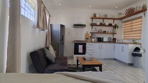 Ett kompakt vardagsrum med en soffa, ett soffbord och en liten köksdel.