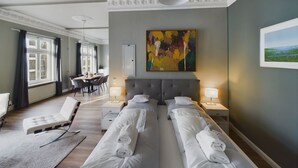 A hotel room with a bed, bedside tables, a desk, and a chair. There is a painting on the wall and a window with curtains. - Art Apartments (Hamburg)