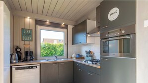 Una cocina moderna con gabinetes grises, un refrigerador de acero inoxidable y un horno empotrado.