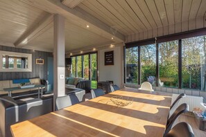 A modern dining area with a wooden table, chairs, and a view of the outdoors. - Julianadorp Family Home (Julianadorp)