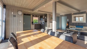 Un espacio habitable amplio con una gran mesa de comedor de madera, una cocina integrada y una zona de estar acogedora con sofá y mesa de centro.