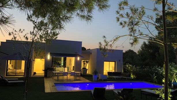 Een modern huis met een zwembad, grote ramen en een terras.