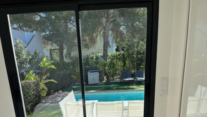 Een slaapkamer met een groot bed, uitzicht op een zwembad en een balkon.