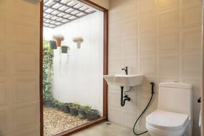 Un baño con inodoro blanco, lavabo y zona de ducha.