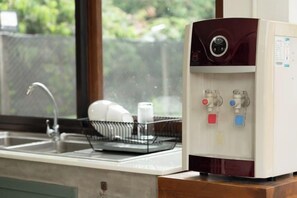 Dispensador de agua con dos salidas y un escurreplatos con platos y una botella.