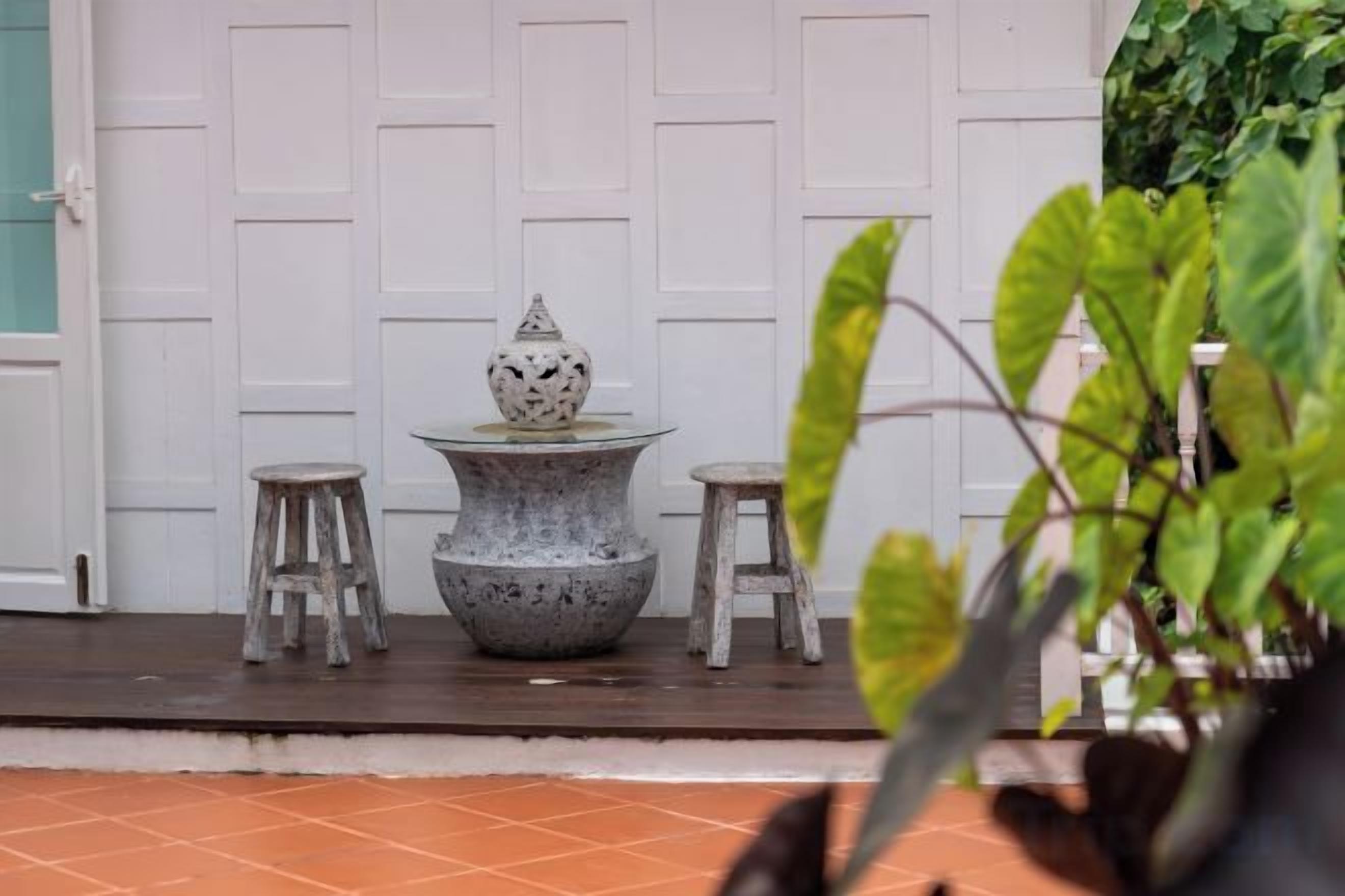 A white door, a stone table with a decorative item, and two stools in front of it.