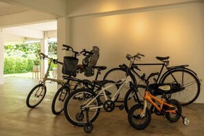 Un espacio interior bien iluminado con zona de almacenamiento para bicicletas, que incluye varias bicicletas, una tándem y una bicicleta infantil.