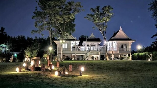 A large, two-story building with a prominent balcony and a distinctive roof structure. - Phi Private Villa: Luxury 4 beds Riverside & Pool: Near old townBreakfast, Laundry, Free pickup (Chiang Mai)