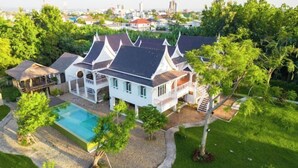 A large white house with multiple gabled roofs, a swimming pool, and lush greenery. - Phi Private Villa: Luxury 4 beds Riverside & Pool: Near old townBreakfast, Laundry, Free pickup (Chiang Mai)