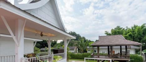 A white building with a covered porch and a gazebo in the background.