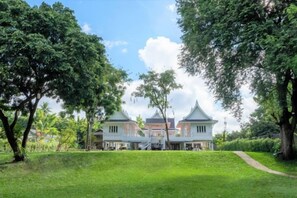 A large, multi-story building with a traditional architectural style, surrounded by lush greenery and a well-maintained lawn. - Phi Private Villa: Luxury 4 beds Riverside & Pool: Near old townBreakfast, Laundry, Free pickup (Chiang Mai)